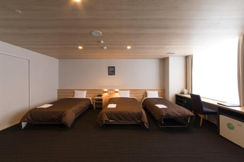 a hotel room with two beds and a desk at Izumisano Center Hotel Kansai International Airport in Izumi-Sano