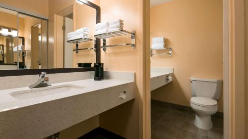 a bathroom with a toilet and a sink and a mirror at Best Western of Olds in Olds