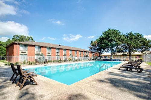 a swimming pool with two chairs and a building at Best Western Plus Guildwood Inn in Sarnia