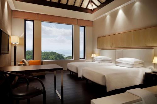 a hotel room with two beds and a desk and windows at Park Hyatt Ningbo Resort & Spa in Ningbo