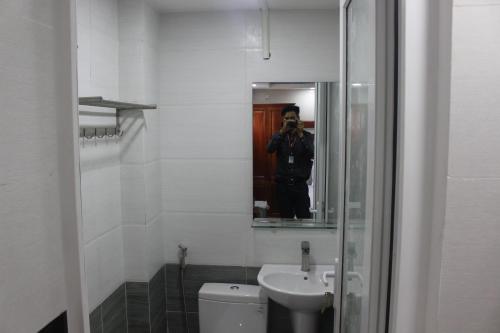Hotel MTT في مدينة هوشي منه: رجل يلتقط صورة للحمام مع مرآة