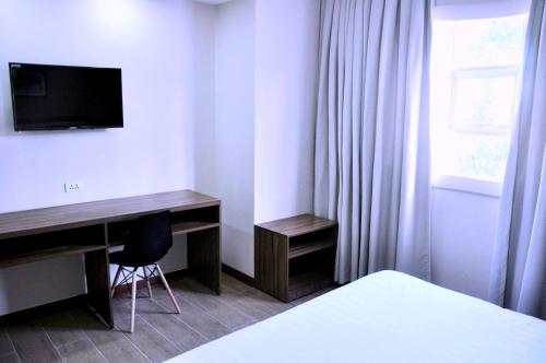 1 dormitorio con escritorio, TV y cama en S Hotel & Residences, en Cebú