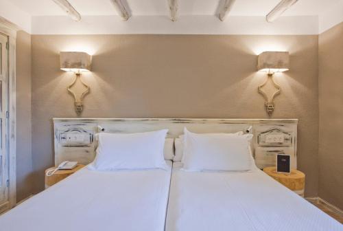 two beds in a room with two lamps on the wall at Hotel Luze El Toro in Berrioplano