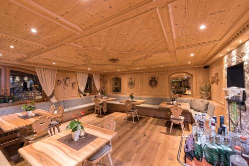 a restaurant with wooden ceilings and tables and chairs at Hotel Welponer in Selva di Val Gardena