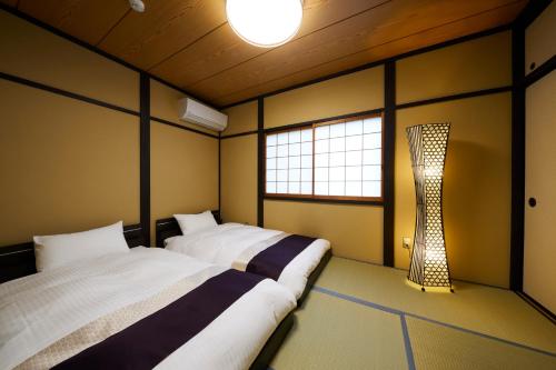 Zimmer mit 2 Betten und einer Lampe in der Unterkunft Rinn Yasaka Kodaiji in Kyoto