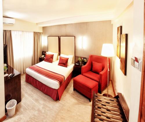 Habitación de hotel con cama y silla roja en The Zehneria Hotel, en Nairobi