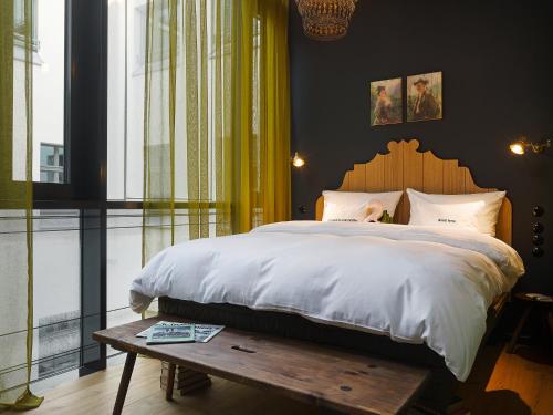 a bedroom with a large bed and a wooden table at 25hours Hotel The Royal Bavarian in Munich