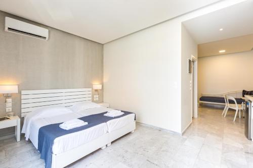 a bedroom with a large white bed and a table at Meltemi Coast Suites in Rethymno Town