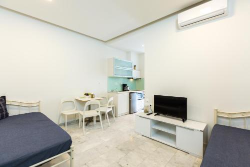 a room with a bed and a tv and a kitchen at Meltemi Coast Suites in Rethymno Town