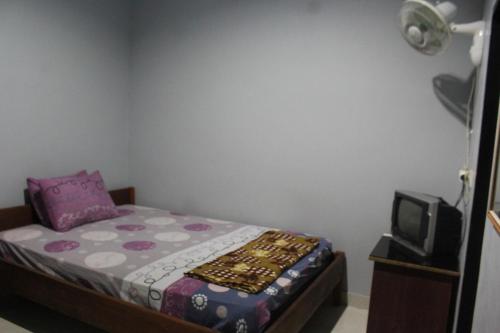 a small bedroom with a bed and a tv at Penginapan Artha in Praya