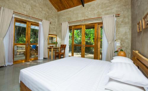 a bedroom with a bed and a table and windows at Valley Village Resort Phu Quoc in Phú Quốc