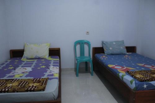 a bedroom with two beds and a blue chair at Penginapan Artha in Praya