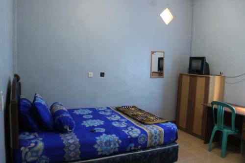a bedroom with a bed and a table and a television at Penginapan Artha in Praya