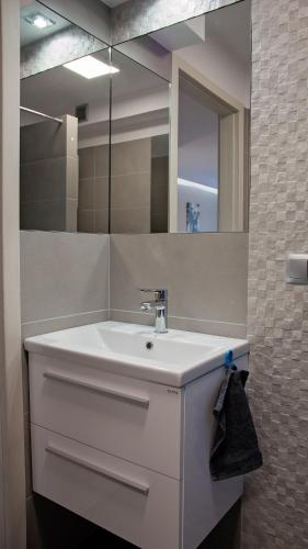 a bathroom with a white sink and a mirror at Apartament Piano 2 in Racibórz