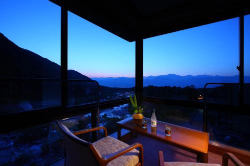 a room with a table and chairs and windows at Futari Shizuka in Komagane