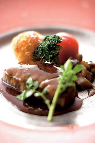 a plate of food with meat and broccoli and a tomato at Futari Shizuka in Komagane