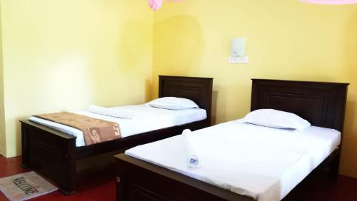 twee bedden in een kamer met witte lakens bij Araliya Self Cooking Resort Dambulla in Dambulla