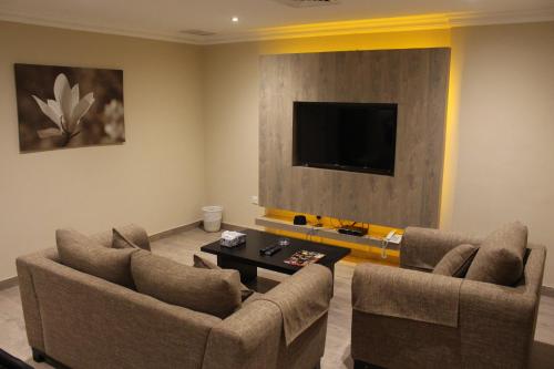 a living room with two chairs and a flat screen tv at Terrace Furnished Apartments- Salmiya in Kuwait