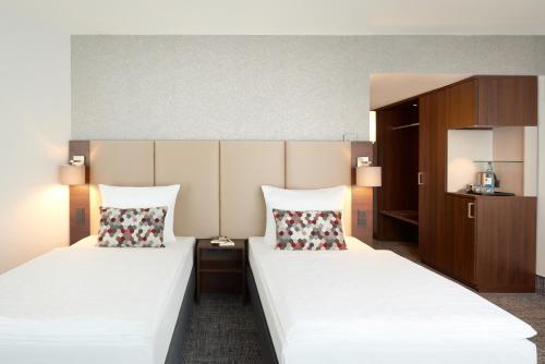 two beds in a hotel room with two pillows at Dorint An den Westfalenhallen Dortmund in Dortmund