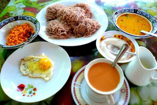 Rohan Villa في هيكادوا: طاولة مع أطباق من الطعام وكوب من القهوة