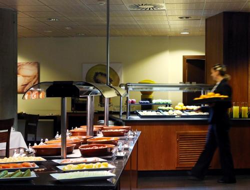 a woman standing in front of a buffet line with food at HG Alto Aragón in Formigal