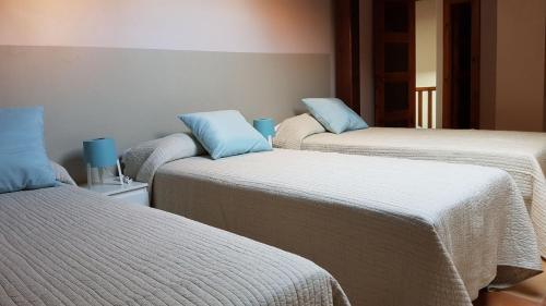 three beds in a room with blue pillows on them at Apartamento de Lujo Av. Barber in Toledo