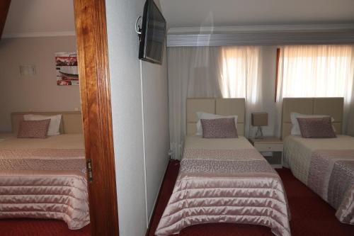 a hotel room with two beds and a television at Hotel Contriz in Póvoa de Varzim