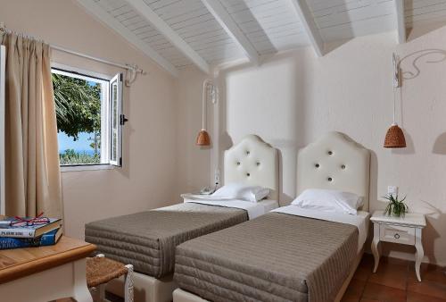 two beds in a white room with a window at Marni Village in Hersonissos