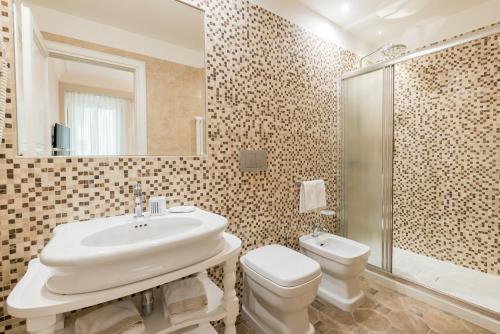 La salle de bains est pourvue d'un lavabo, de toilettes et d'un miroir. dans l'établissement Altarocca Embassy Rome, à Rome