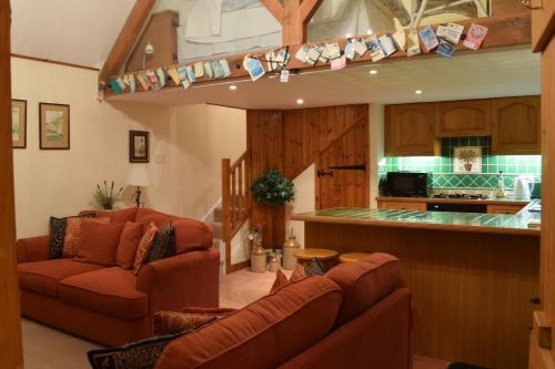 a living room with two couches and a kitchen at Swallows' Barn in Corby