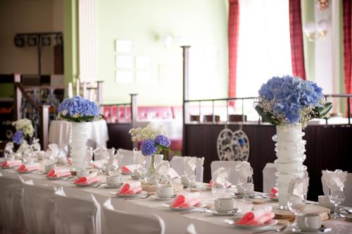 a long table with white chairs and vases with flowers at Historische Spitzgrundmühle in Coswig