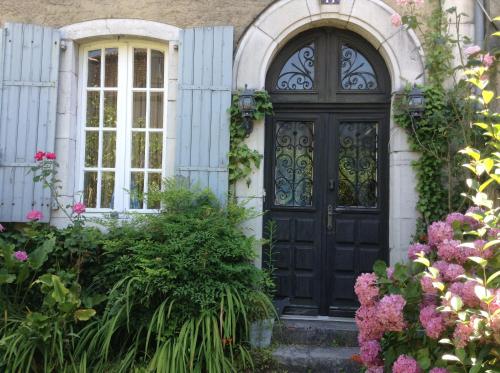 une porte noire dans une maison fleurie dans l'établissement Laroumette, à Salies-de-Béarn