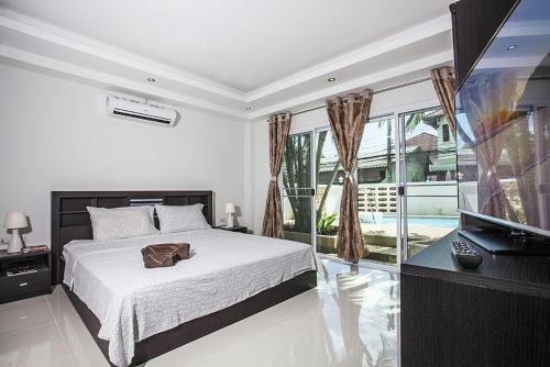 a bedroom with a bed and a flat screen tv at ViLLa JUNGLE 3 BEDROOMS in Kamala Beach