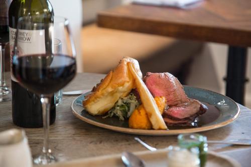 a plate of food on a table with a glass of wine at The Museum Inn in Farnham