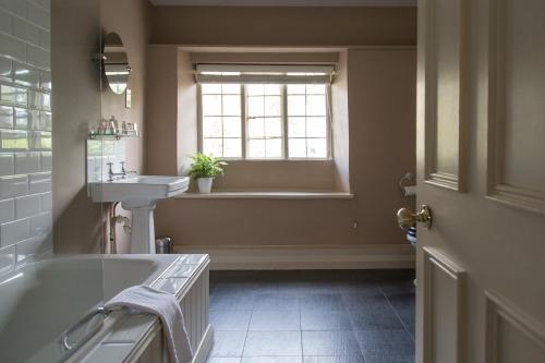 a bathroom with a tub and a sink and a window at The Museum Inn in Farnham