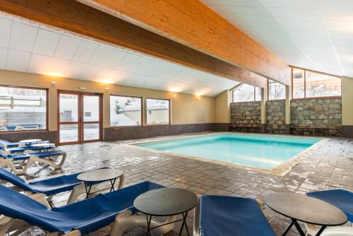 - une piscine avec des chaises bleues, une table et des chaises dans l'établissement travelski home select - Résidence Les Chalets du Galibier, à Valloire
