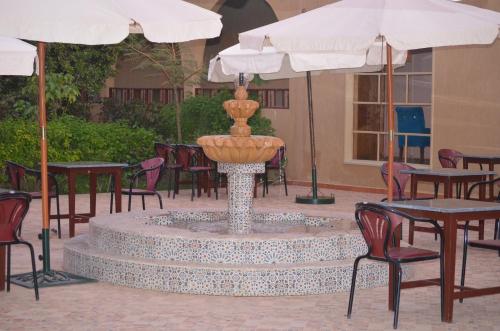 a fountain in a courtyard with chairs and umbrellas at Almounia Hotel & Spa in Taroudant