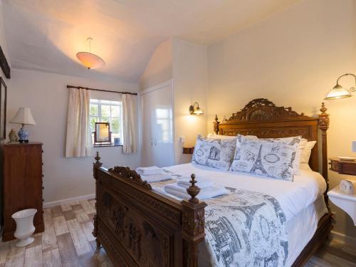 - une chambre avec un grand lit en bois et des oreillers dans l'établissement Box Cottage, à Broadway