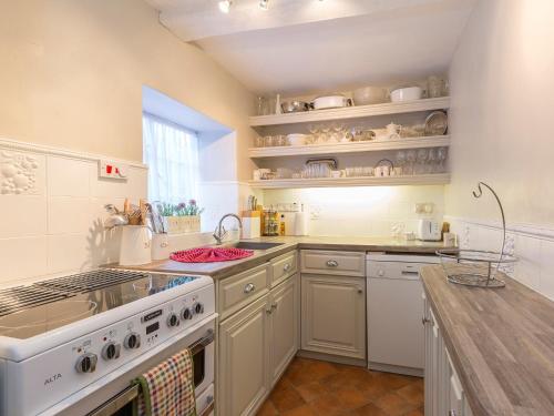 a kitchen with a stove and a sink and a counter at Box Cottage in Broadway