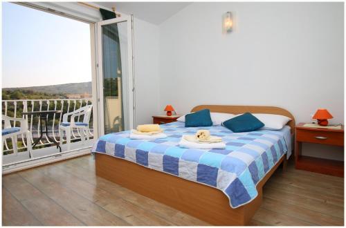a bedroom with a bed and a balcony with a view at Apartments HULJEV in Primošten