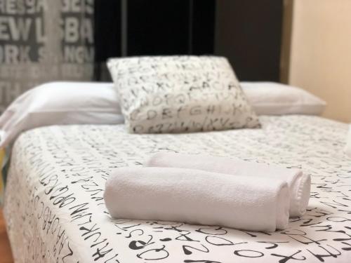 two beds with white sheets and towels on them at Apartamento Torre del Clavero in Salamanca