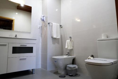 a white bathroom with a toilet and a sink at Hotel Contriz in Póvoa de Varzim