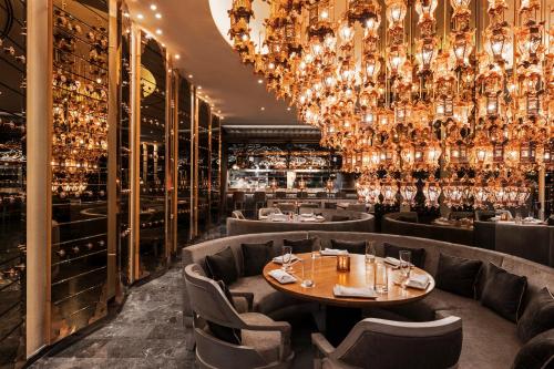 um restaurante com um grande lustre e mesas e cadeiras em Mondrian Doha em Doha