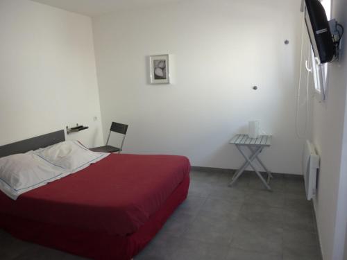 1 dormitorio con cama roja y mesa pequeña en Hotel de l'Avenue en Bonson