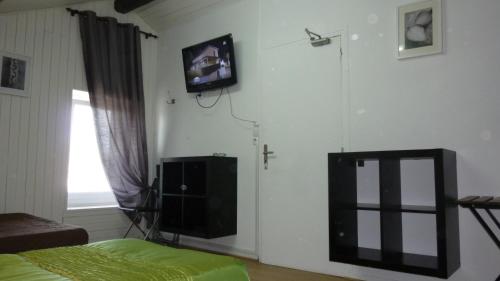 a bedroom with a tv on the wall and a bed at Hotel de l'Avenue in Bonson