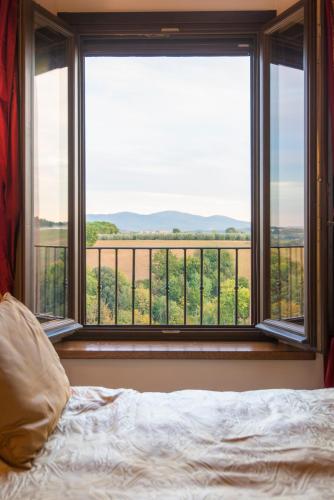a bedroom with a bed and a large window at Palazzo Pacini in Colle Val D'Elsa