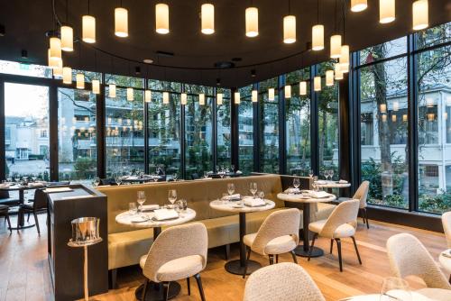 een restaurant met tafels en stoelen en grote ramen bij Pillows Grand Boutique Hotel Ter Borch Zwolle in Zwolle