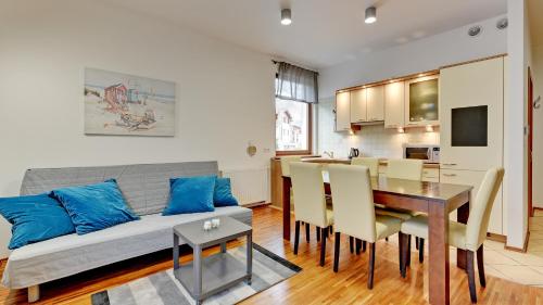 a living room with a couch and a dining room at Dom & House - Apartamenty Neptun Park in Gdańsk