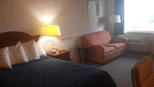 ein Schlafzimmer mit einem Bett, einem Stuhl und einer Lampe in der Unterkunft Audrey's Motel in Mound City