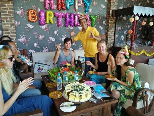 Un groupe de personnes assises autour d'une table avec un gâteau d'anniversaire dans l'établissement Clover Homestay, à Probolinggo